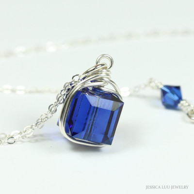 Dark sapphire blue 8mm faceted cube shaped Austrian crystal solitaire pendant in sterling silver wire wrapped setting on 18 inch long chain necklace handmade by Jessica Luu Jewelry Dark sapphire blue 8mm faceted cube shaped Austrian crystal solitaire pendant in sterling silver wire wrapped setting on 18 inch long chain necklace handmade by Jessica Luu Jewelry