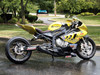 Brocks Performance Brocks Alien Head 2 Full Exhaust 14" Muffler Black BMW S1000RR (10-14) and S1000R (14-16), black and yellow motorcycle parked on a wet pavement with a green park background.