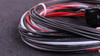 MaxxECU Race Flying Lead Wiring Harness Connector 2, close-up of the black, white, and red electrical wires arranged in a circular loop on a dark surface.