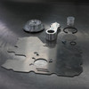 Vance & Hines Swinging Oil Pick-Up Kit Suzuki GS1100/1150, motorcycle engine repair parts including a metal oil pick-up, gasket, clips, and small components arranged on a dark metal surface.