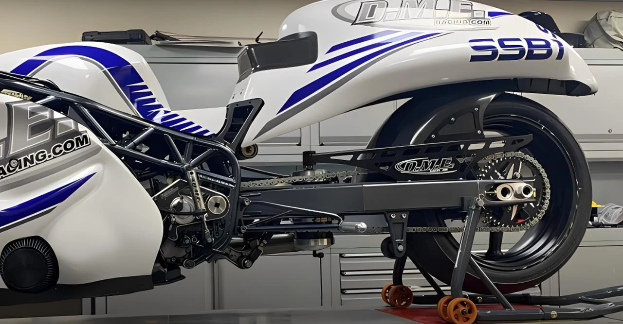 DME Aluminum Swingarm Suzuki Hayabusa (08-20), close-up of the black aluminum swingarm attached to a motorcycle with blue and white bodywork, showing detailed construction and chain drive system.