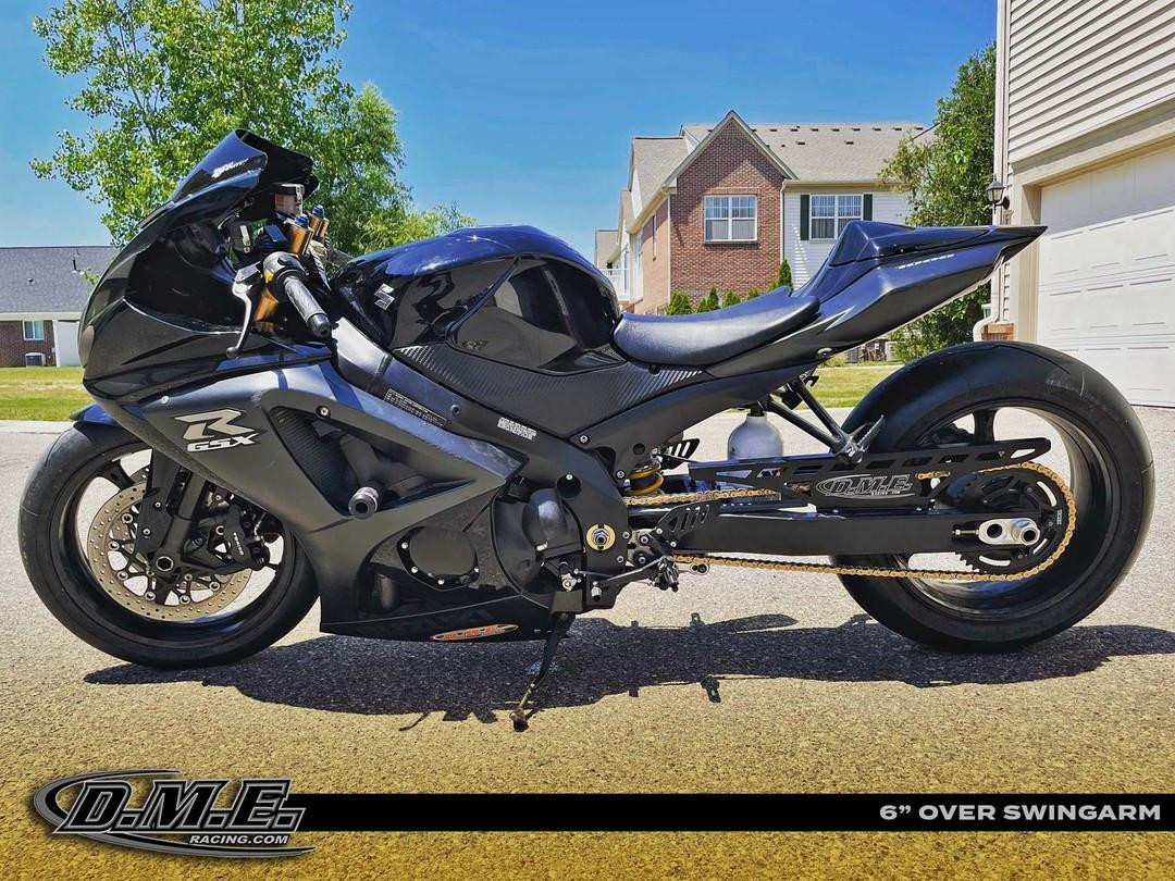 DME Aluminum Swingarm Kawasaki ZX10R (08-10), motorcycle with black aluminum swingarm, black bodywork, and sporty design, parked on a suburban street with houses and trees in the background.