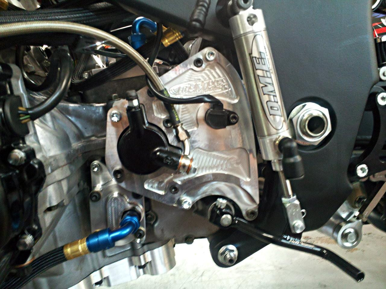 DME Billet Case Saver Front Sprocket Cover Suzuki Hayabusa (99-07), close-up of metallic and black racing motorcycle part on engine with branding and various mounted components.