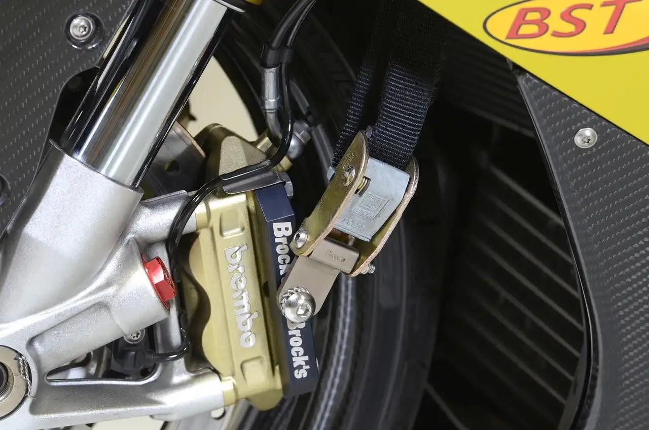 Brocks Performance Brocks Front End Lowering Strap End Kit, motorcycle front suspension with a gold-colored strap end fitting, black strap, and silver mounting bracket.