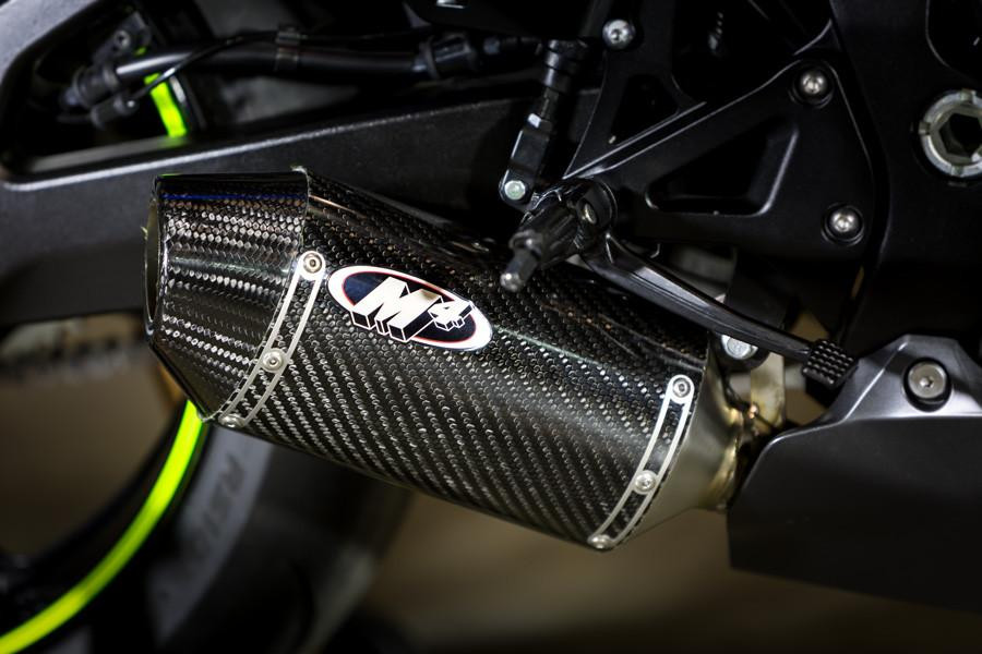 M4 Performance Exhausts M4 Street Slayer Carbon Exhaust Suzuki GSXR1000 (17-27), close-up of black carbon fiber motorcycle exhaust with M4 logo and mounting brackets.