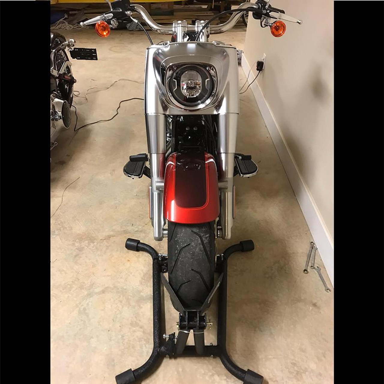 Baxley LA Chock, front view of a motorcycle with a red fender and a silver headlamp, mounted on a display stand inside a showroom.