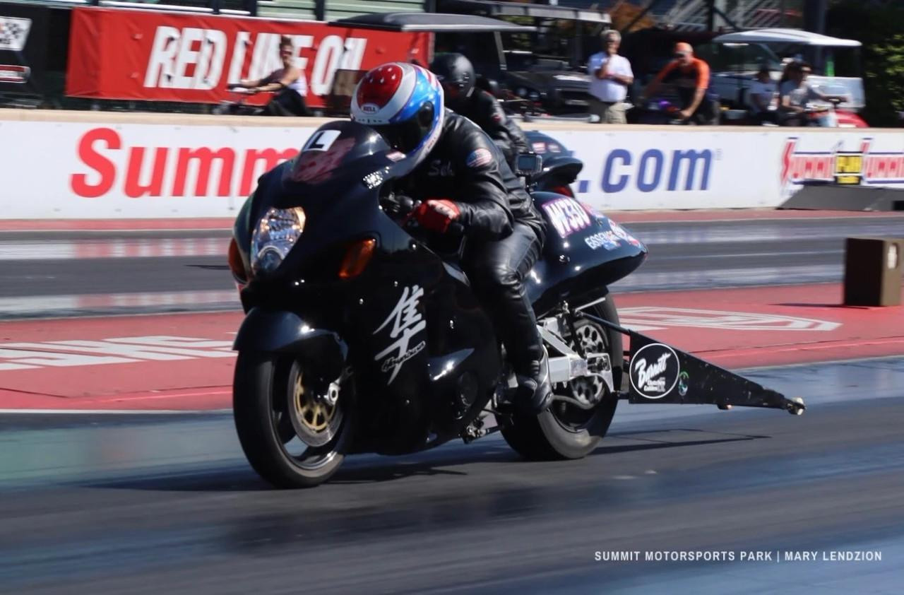Mickey Thompson Motorcycle Slicks, Mickey Thompson 3221 26/7-17 ET Drag Rear Slick, motorcycle racing on a drag strip with a black motorcycle and rider wearing racing gear.