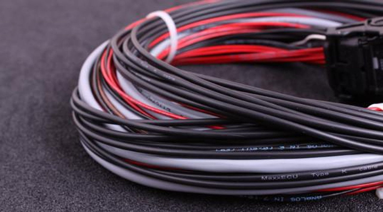 MaxxECU Race Flying Lead Wiring Harness Connector 2, close-up of the black, white, and red electrical wires arranged in a circular loop on a dark surface.