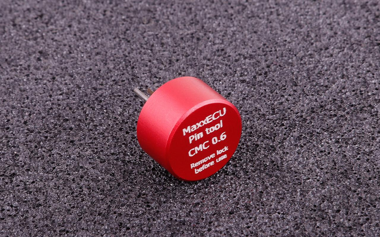 MaxxECU CMC 0.6 Terminal Removal Tool, small red cylindrical pin tool on a black textured surface. MaxxECU CMC 0.6 Terminal Removal Tool, small red cylindrical pin tool on a black textured surface.