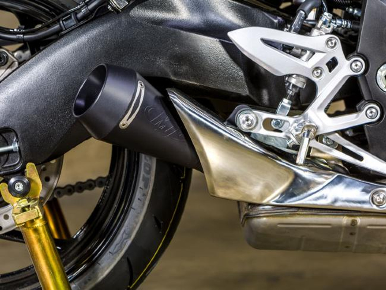 M4 Performance Exhausts M4 GP Black Slip On Exhaust Suzuki GSX-S 1000/1000F (16-19), close-up view of the black and chrome motorcycle exhaust system installed on the bike's undercarriage.