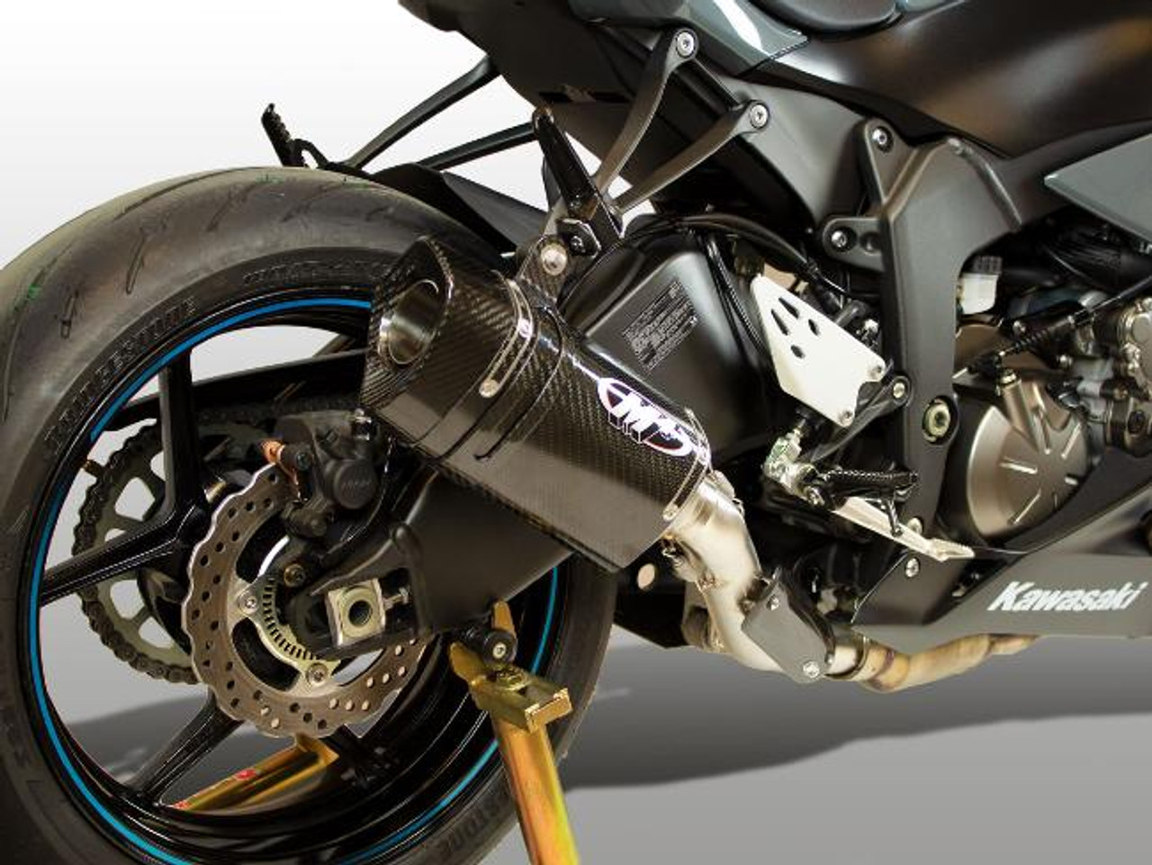 M4 Performance Exhausts M4 Tech1 Carbon Fiber Slip On Exhaust for Kawasaki ZX-6R (09-25), close-up of motorcycle's rear with carbon fiber muffler, rear wheel, and chassis details.