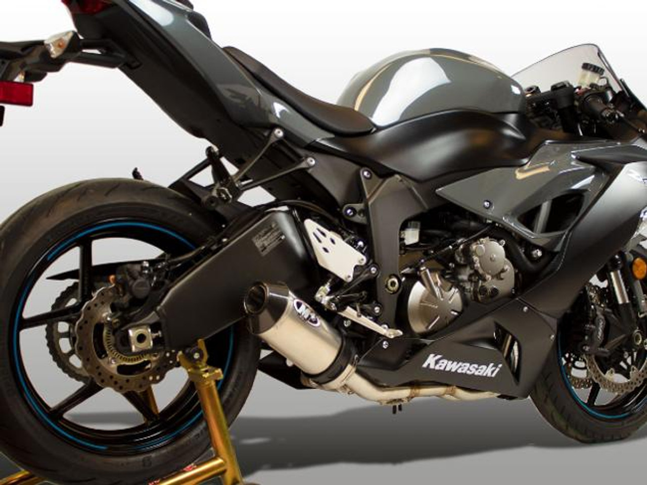 M4 Performance Exhausts M4 Street Slayer Titanium Exhaust Kawasaki ZX-6R (09-25), close-up of motorcycle with black and titanium exhaust system, rear wheel, and sleek aerodynamic body.