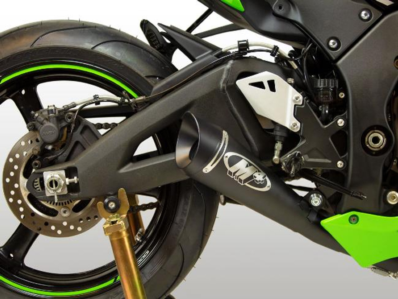 M4 Performance Exhausts M4 GP Black Exhaust Kawasaki ZX-10R (16-20), close-up of the black motorcycle exhaust system with a skull logo, rear wheel, and part of the frame.