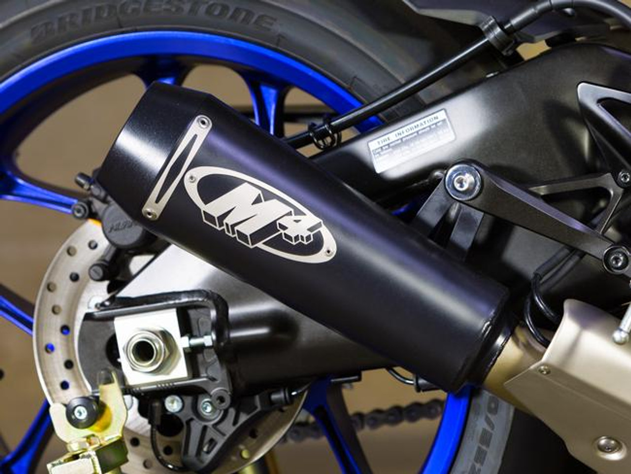 M4 Performance Exhausts M4 GP2 Black Slip On Exhaust Yamaha YZF-R1 (15-24), close-up view of the sleek black exhaust with M4 logo installed on the motorcycle with a blue rear wheel.