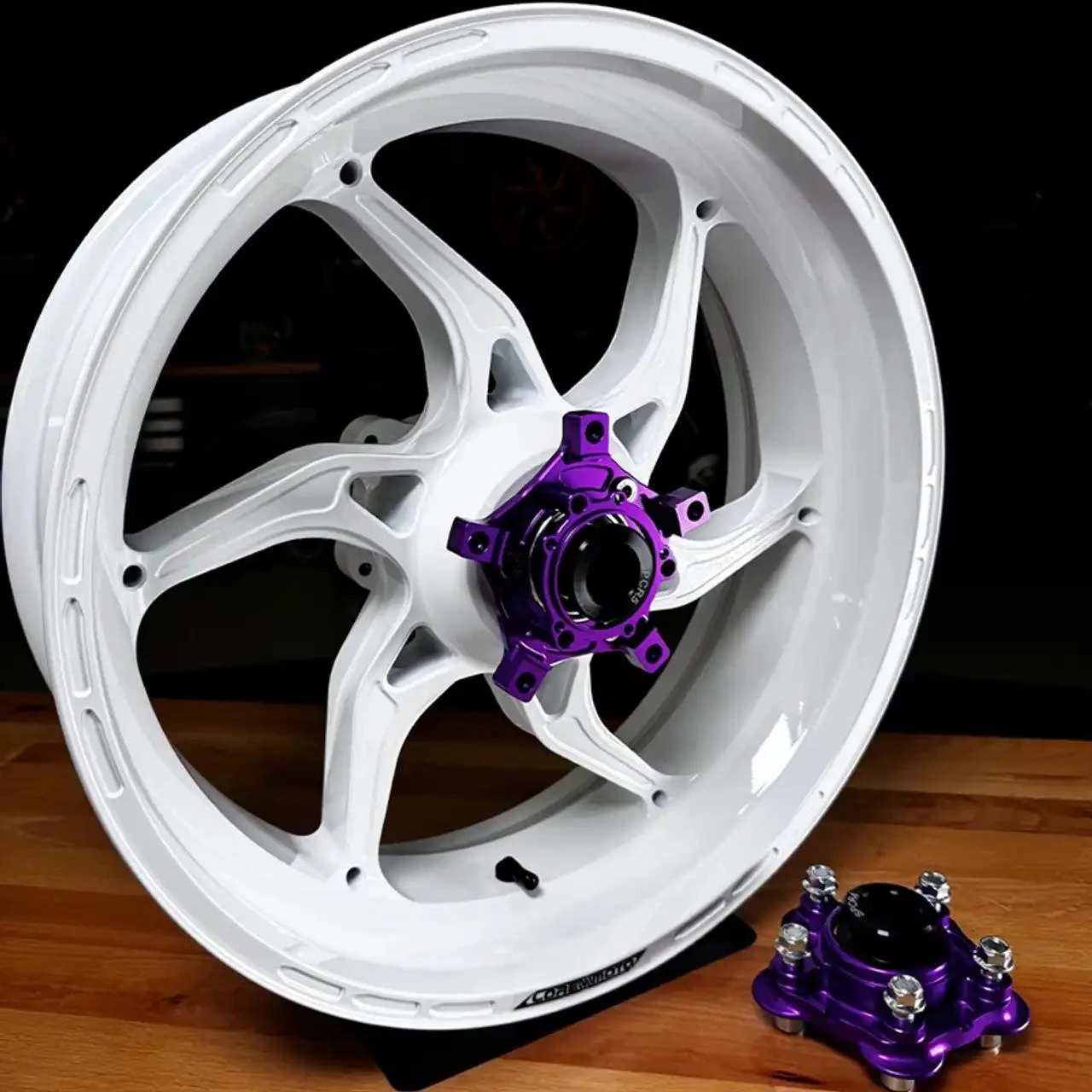 Coremoto Apex-6 Forged Aluminum Wheels Yamaha YZF-R1 (15-26), a white forged aluminum wheel with purple anodized hub and rotor adapter, shown with a black background and wooden surface.