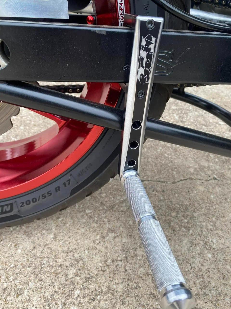 Total Performance Cycle TPC Swingarm Footpegs, close-up of motorcycle footpeg mounted on swingarm with grip surface for rider stability. Total Performance Cycle TPC Swingarm Footpegs, close-up of motorcycle footpeg mounted on swingarm with grip surface for rider stability.