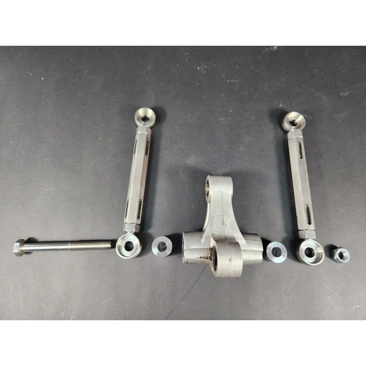 VooDoo Fully Adjustable Lowering Links Kawasaki ZX-14R (06-25), metal lowering links with adjustable rods and mounting hardware arranged on a black surface.