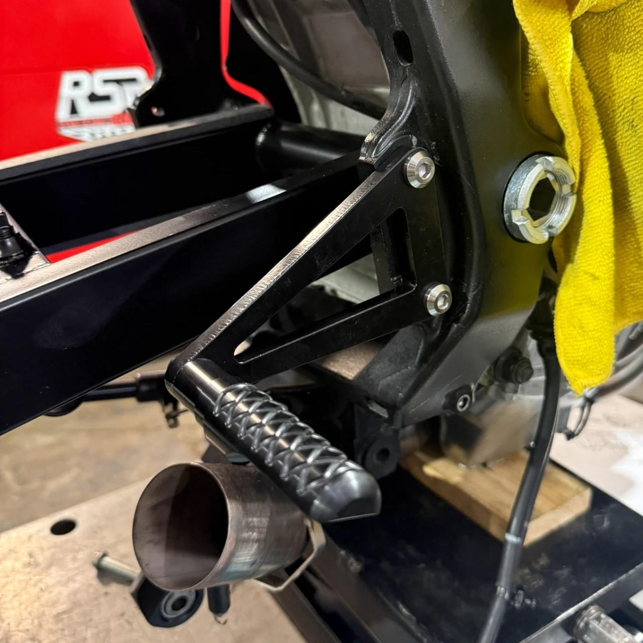 Schnitz Racing Motorcycle Performance Parts Lightweight Rear Sets Suzuki GSXR1000 (17-26), close-up of black rearsets installed on a motorcycle with footpeg and foot lever details.