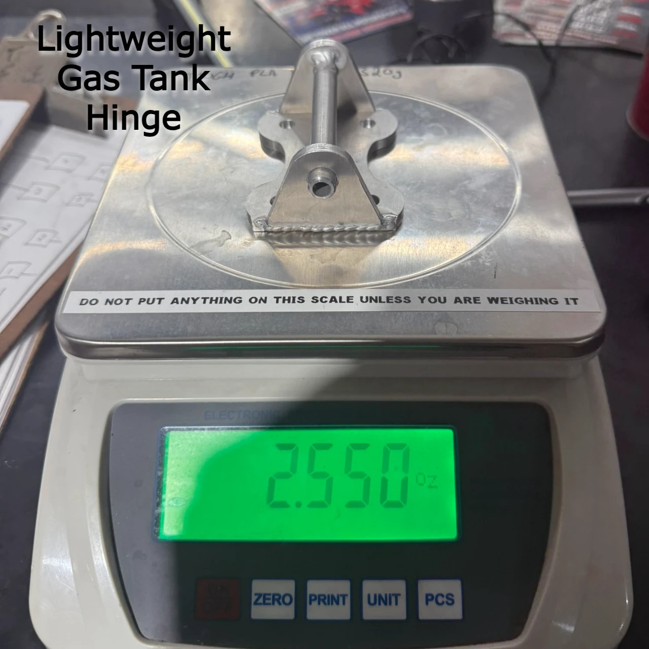 Lightweight Gas Tank Hinge Suzuki GSXR1000 (17-25) on scale showing weight