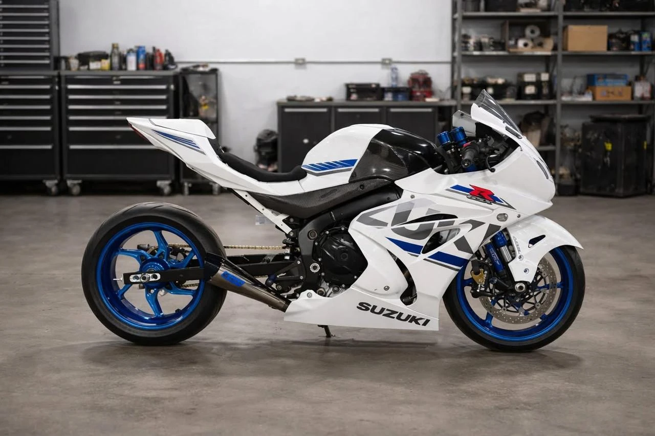 Lo Pro Racing Alcantara Cut Seat GSXR1000 (17-25), white and blue racing motorcycle with custom seat in a workshop.