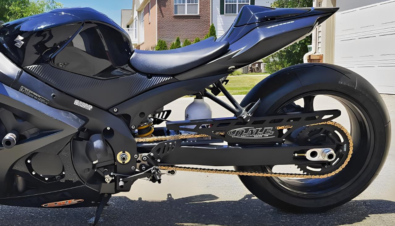 DME Racing Motorcycle Parts DME Aluminum Swingarm Honda CBR1000RR (04-25), motorcycle swingarm on black frame with gold chain and black tires.