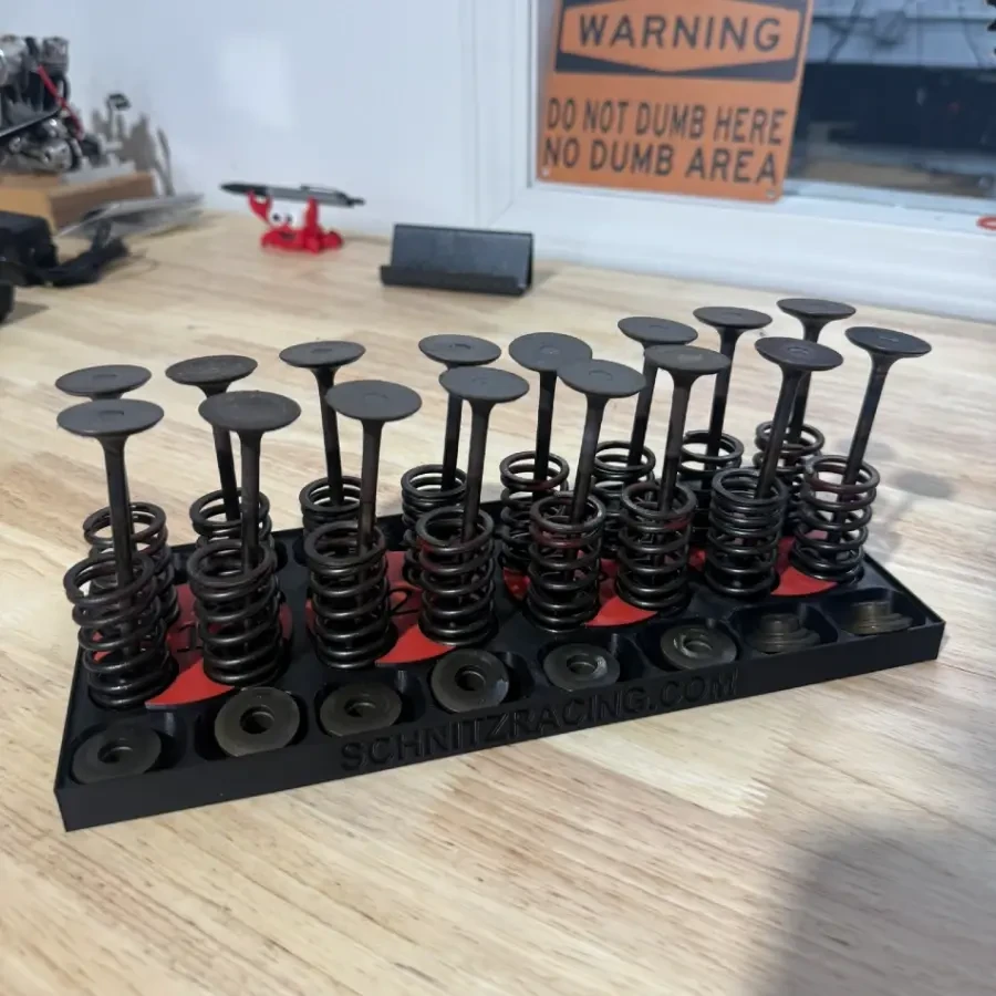 Schnitz Racing Motorcycle Performance Parts Schnitz Cylinder Head Organizer, black metal organizer with multiple metal cylinder head holders arranged in rows on a wooden workbench
