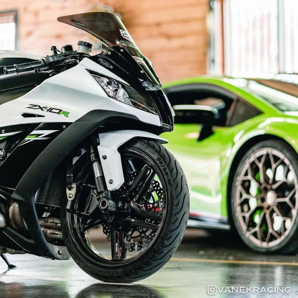 DME Racing Motorcycle Parts DME Front Fender Lowering Brackets Kawasaki ZX-10R (11-26), close-up of a black and white sport motorcycle with lowered front fender, in a garage setting