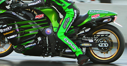 DME Aluminum Swingarm Kawasaki ZX14R (06-11), fitness motorcycle racing bike with a shiny black and green color scheme, branding and sponsor logos including MS D, Continental, Brock's, and Carrillo, during a race. Loading Image