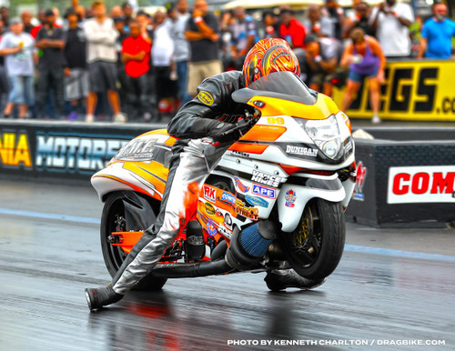 Dunlop K330 Front 100/80-16 Front Tire, motorcycle racing bike performing a burnout on race track with crowd in background. Dunlop K330 Front 100/80-16 Front Tire, motorcycle racing bike performing a burnout on race track with crowd in background.