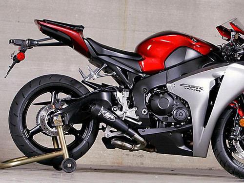 M4 Performance Exhausts M4 GP Black Slip On Exhaust Honda CBR1000RR (08-16), motorcycle with red and silver body and black exhaust system in a garage setting.