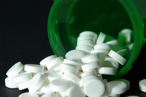 green pill bottle toppled over revealing pills 