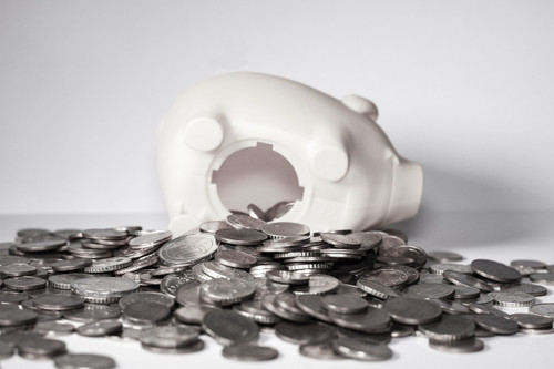 coins spilling out of a white piggy bank