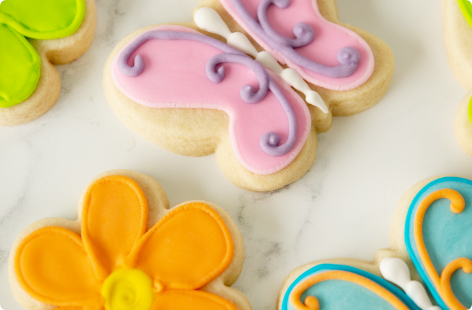 A closeup of spring themed sugar cookies with pastel icing, including a flower, and two butterflies