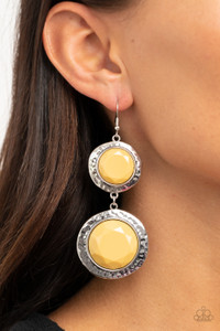 Varying in size, a pair of faceted yellow beads are pressed into the shimmery centers of hammered silver frames as they link into a colorfully rustic lure. Earring attaches to a standard fishhook fitting.

Sold as one pair of earrings.