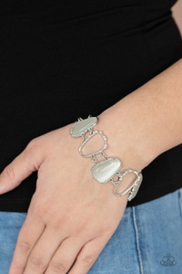 Encased in studded silver frames, a tranquil collection of asymmetrical white cat’s eye stone teardrops and airy silver frames delicately link around the wrist for an ethereally sparkly display. A sprinkling of rhinestones accent the open frames, adding a touch of elegance to the piece.
Features an adjustable clasp closure. Encased in studded silver frames, a tranquil collection of asymmetrical white cat’s eye stone teardrops and airy silver frames delicately link around the wrist for an ethereally sparkly display. A sprinkling of rhinestones accent the open frames, adding a touch of elegance to the piece.
Features an adjustable clasp closure.