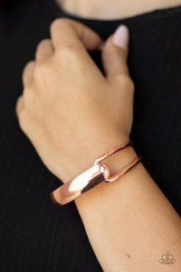 A flat shiny copper bar and airy shiny copper frame delicately overlap around the wrist, creating an oversized cuff-like bangle for a modern twist. Features a hinged closure.

Sold as one individual bracelet.
