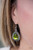 A faceted green teardrop gem is pressed into a shimmery silver frame radiating with studded details and glittery black rhinestones for a magnificent look. Earring attaches to a standard fishhook fitting. Sold as one pair of earrings. A faceted green teardrop gem is pressed into a shimmery silver frame radiating with studded details and glittery black rhinestones for a magnificent look. Earring attaches to a standard fishhook fitting. Sold as one pair of earrings.