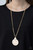 A textured gold disc links with a shell-like frame at the bottom of a section of thick gold chain, creating a summery pendant. Features an adjustable clasp closure.
Sold as one individual necklace. Includes one pair of matching earrings. A textured gold disc links with a shell-like frame at the bottom of a section of thick gold chain, creating a summery pendant. Features an adjustable clasp closure.
Sold as one individual necklace. Includes one pair of matching earrings.