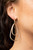 A squiggly gold bar curls around the tops of two teardrop gold frames, creating an abstract hoop. Earring attaches to a standard post fitting. Hoop measures approximately 3/4" in diameter.

Sold as one pair of hoop earrings.