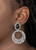Filled with vine-like filigree, an airy silver hoop dangles from the bottom of a studded silver frame dotted with a black teardrop bead for a whimsical fashion. Earring attaches to a standard clip-on fitting.

Sold as one pair of clip-on earrings.