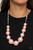 Separated by stacks of smooth and decorative silver rings, a collection of dramatically oversized pink pearls are delicately hand-strung along an invisible wire that attaches to knotted strands of pink cording for a classically handcrafted look. Features an adjustable clasp closure.

Sold as one individual necklace. Includes one pair of matching earrings.