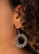 An explosion of round hematite rhinestones and hematite rhinestone dotted silver bars coalesce into a smoldering hoop. Earring attaches to a standard fishhook fitting.

Sold as one pair of earrings.