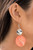 A large pearlescent disc in the spring Pantone® of Burnt Coral is topped by a wavy, sparkling silver disc. The pair sways dramatically from a silver fitting for a breezy finish. Earring attaches to a standard fishhook fitting.

Sold as one pair of earrings.