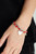 A shiny silver heart dangles from a strand of fiery red beads. It is paired with a strand of round silver beads threaded along a stretchy band for a whimsical display around the wrist.

Sold as one pair of bracelets.
