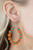 Dotted with turquoise beaded centers, a dainty collection of orange seed beaded floral frames are threaded along a wire hoop for a fabulous floral fashion. Earring attaches to a standard fishhook fitting.

Sold as one pair of earrings.