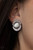 A glowing white cat's eye stone is nestled inside a circular frame of glassy white rhinestones, creating a whimsical centerpiece. Earring attaches to a standard clip-on fitting.

Sold as one pair of clip-on earrings.