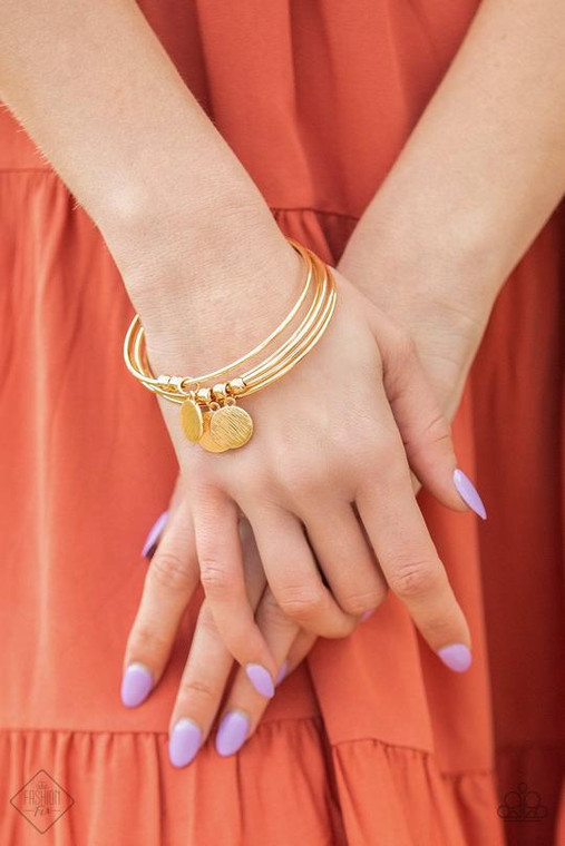 Five classic gold bangles stack up the wrist. A glistening collection of dainty gold beads and textured gold discs slide along two of bangles, creating shimmery charms.

Sold as one individual bracelet.
