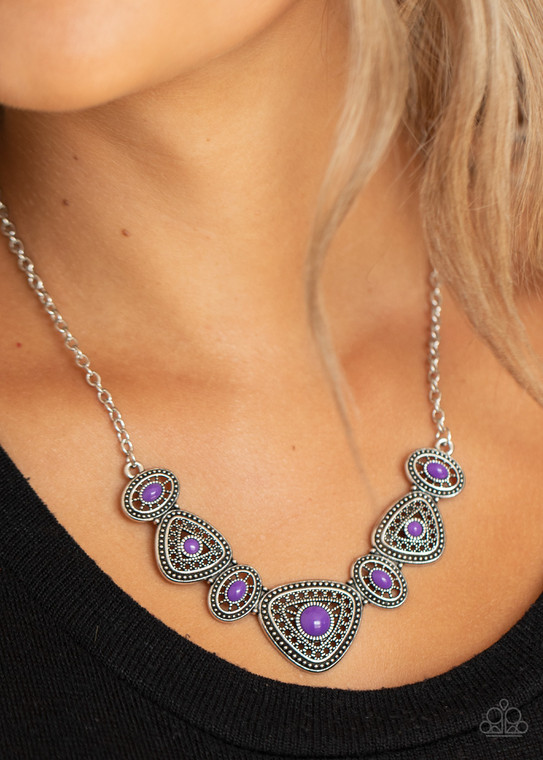 Mismatched purple beads adorn the centers of mismatched silver frames dotted and studded in tribal inspired textures. The oval and triangular silver frames delicately connect in a crescent-shaped pendant, creating a vibrant pop of color below the collar. Features an adjustable clasp closure.

Sold as one individual necklace. Includes one pair of matching earrings.