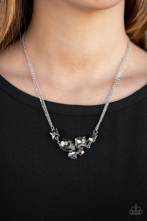 Varying in shape and size, triangular, round, and square cut hematite and smoky rhinestones coalesce into a floating pendant at the bottom of doubled silver chains, creating a stellar shimmer below the collar. Features an adjustable clasp closure.

Sold as one individual necklace. Includes one pair of matching earrings.