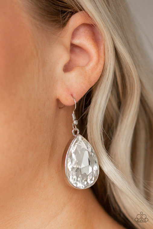 An oversized white teardrop rhinestone is nestled inside of a sleek silver frame for a dramatic look. Earring attaches to a standard fishhook fitting.

Sold as one pair of earrings.